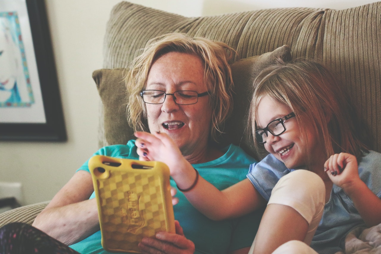 white older woman playing on an ipad with her granddaughter