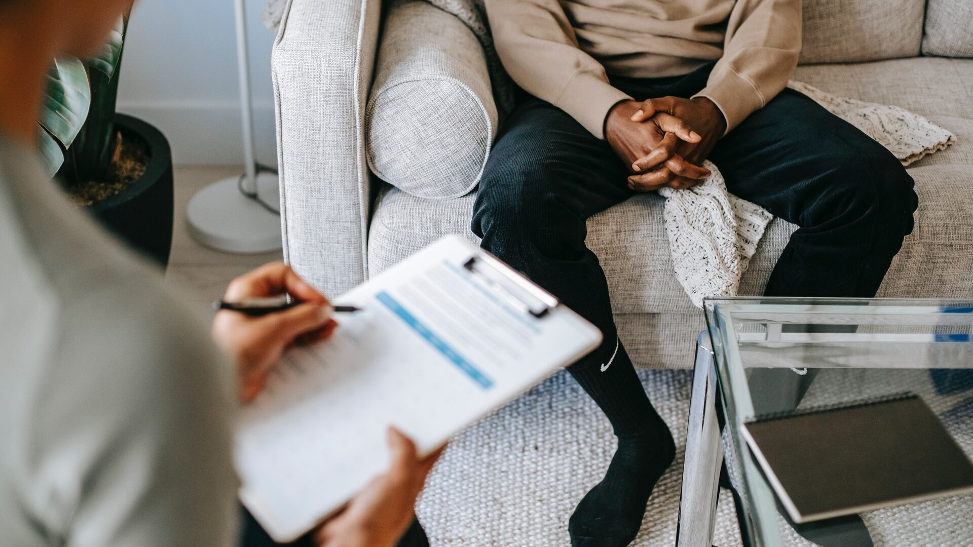 white woman with clipboard interviewing a black man in a living room