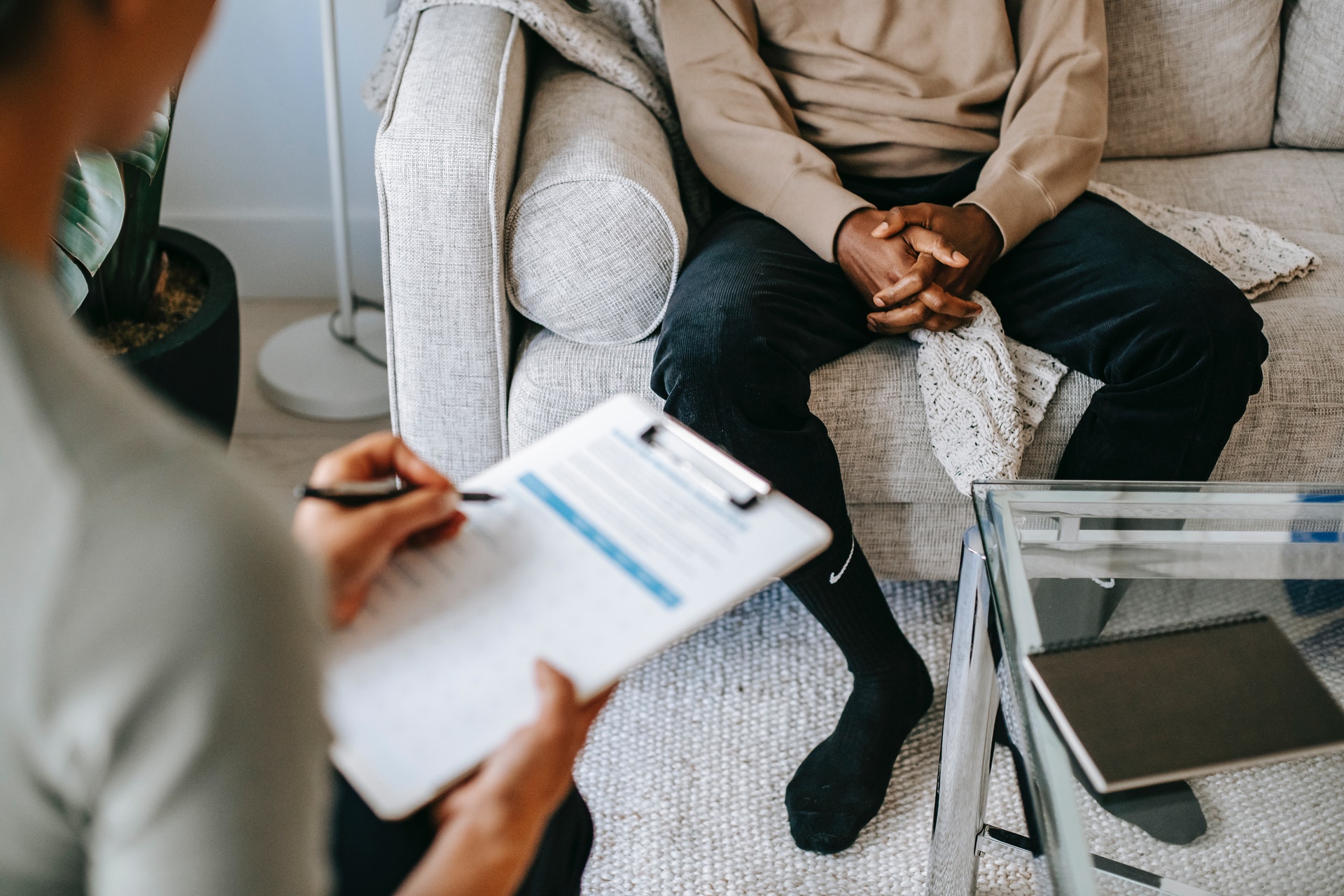white woman with clipboard interviewing a black man in a living room