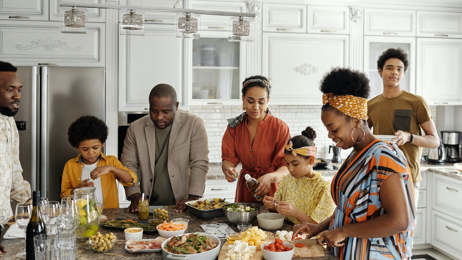 a family of black women, men, and children eating at a table in a kitchen