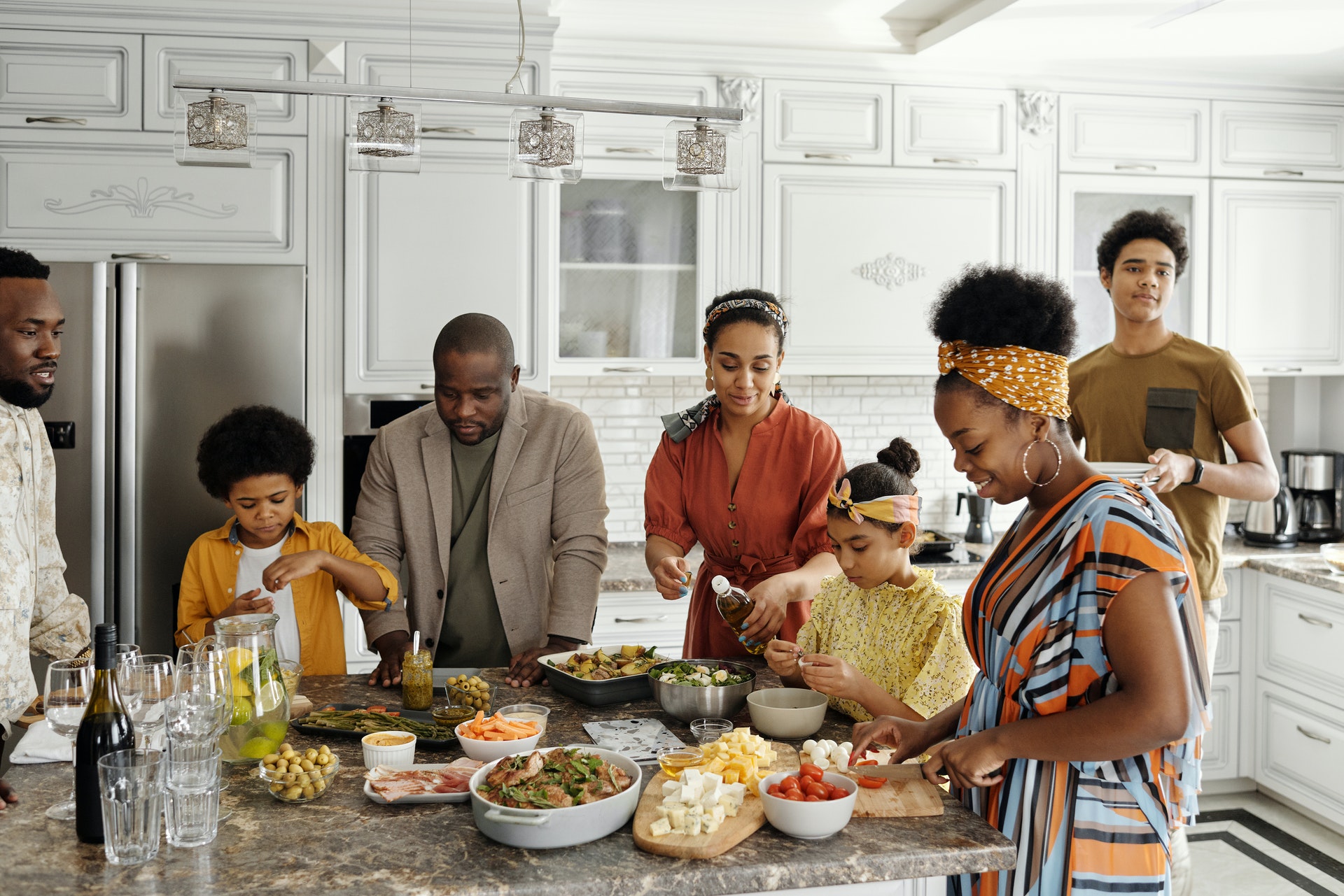 a family of black women, men, and children eating at a table in a kitchen