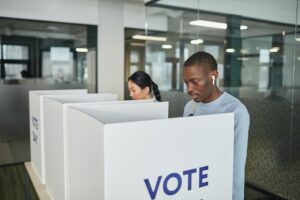 black man and asian woman in booths voting