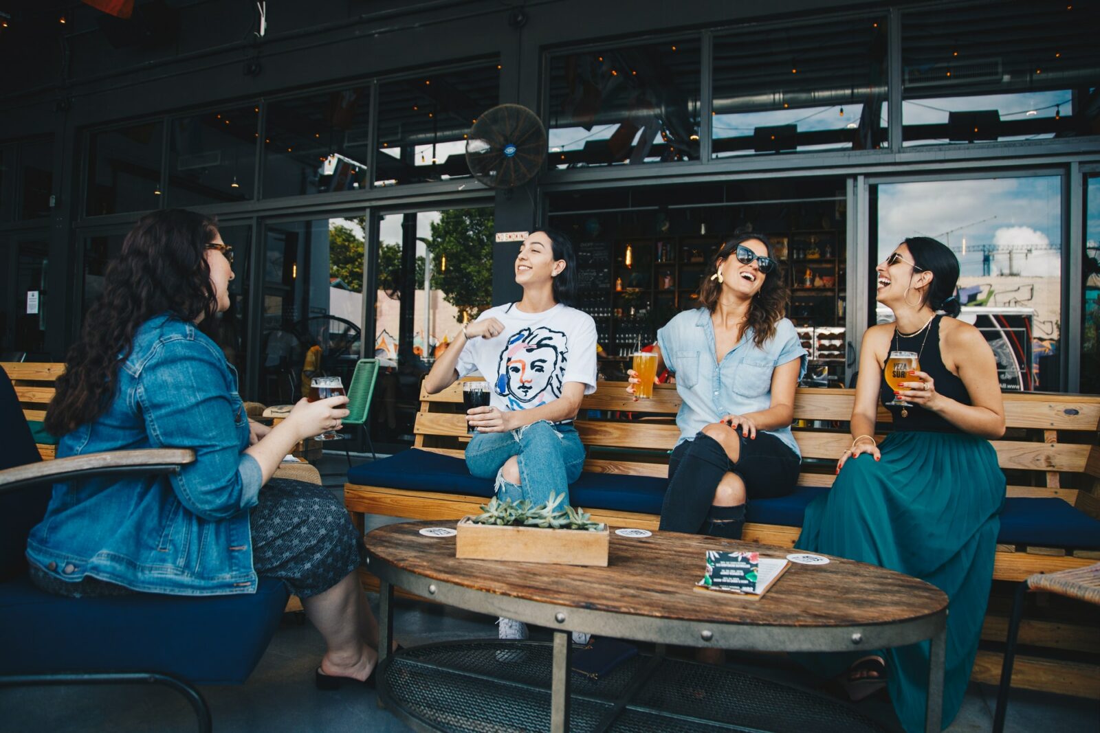 a group of four women—asian, white, black—all having a conversation laughing at a restaurant