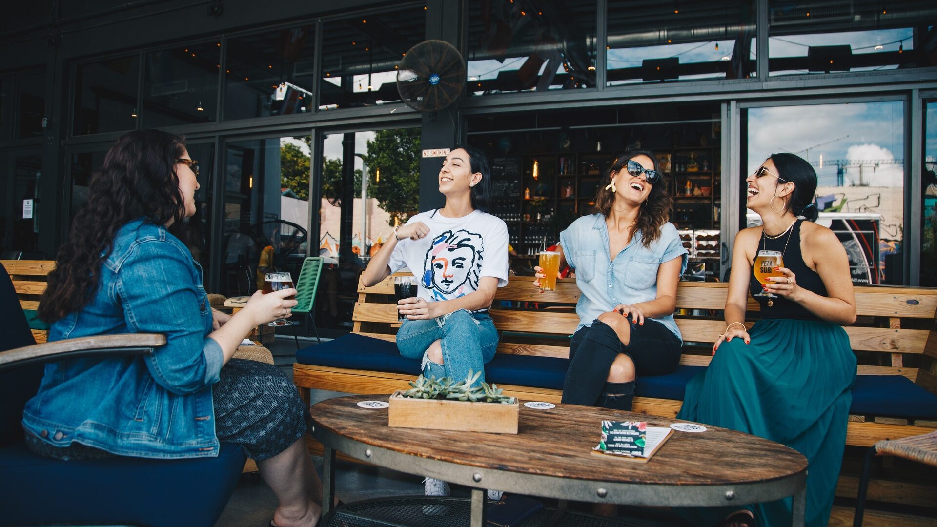 a group of four women—asian, white, black—all having a conversation laughing at a restaurant