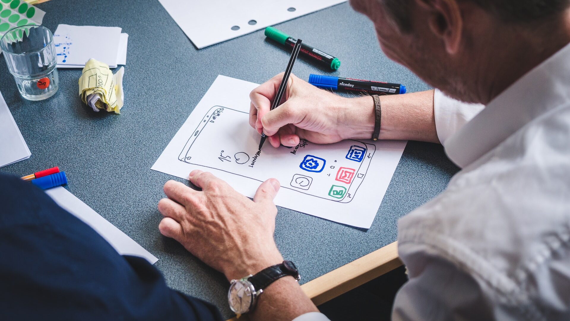 person drawing icons on a paper ux prototype