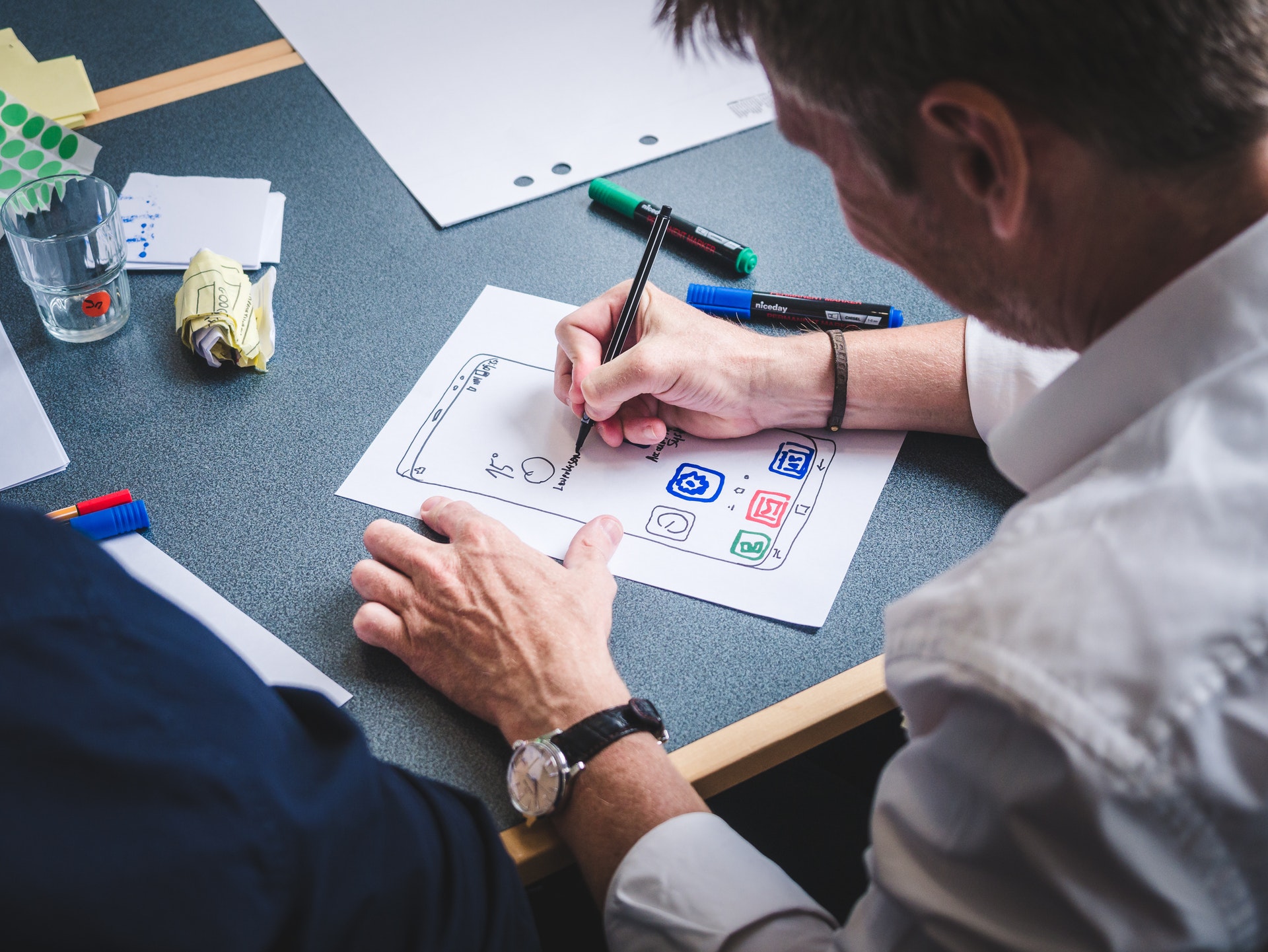 person drawing icons on a paper ux prototype