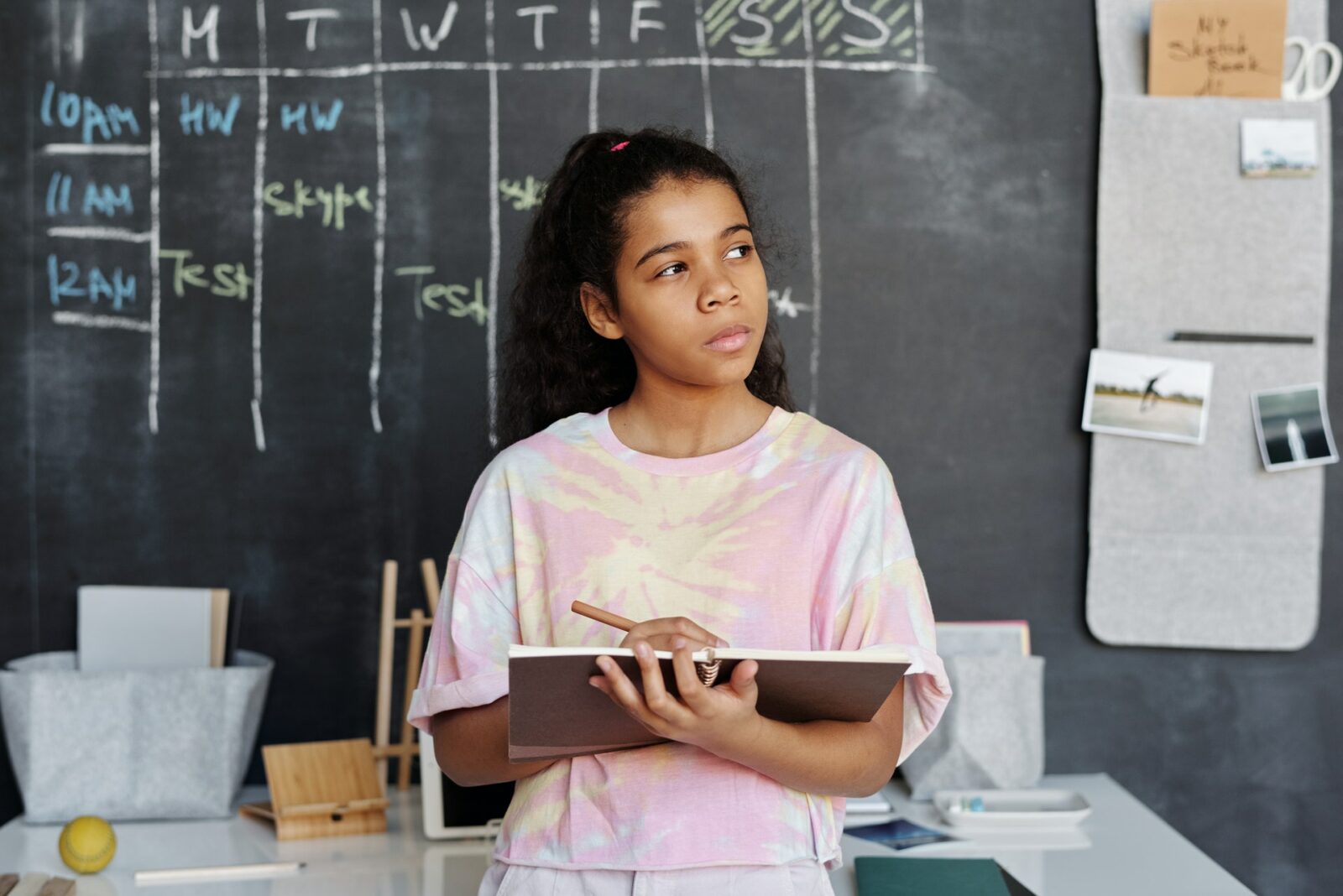 an asian girl holding a pencil and tablet thinking