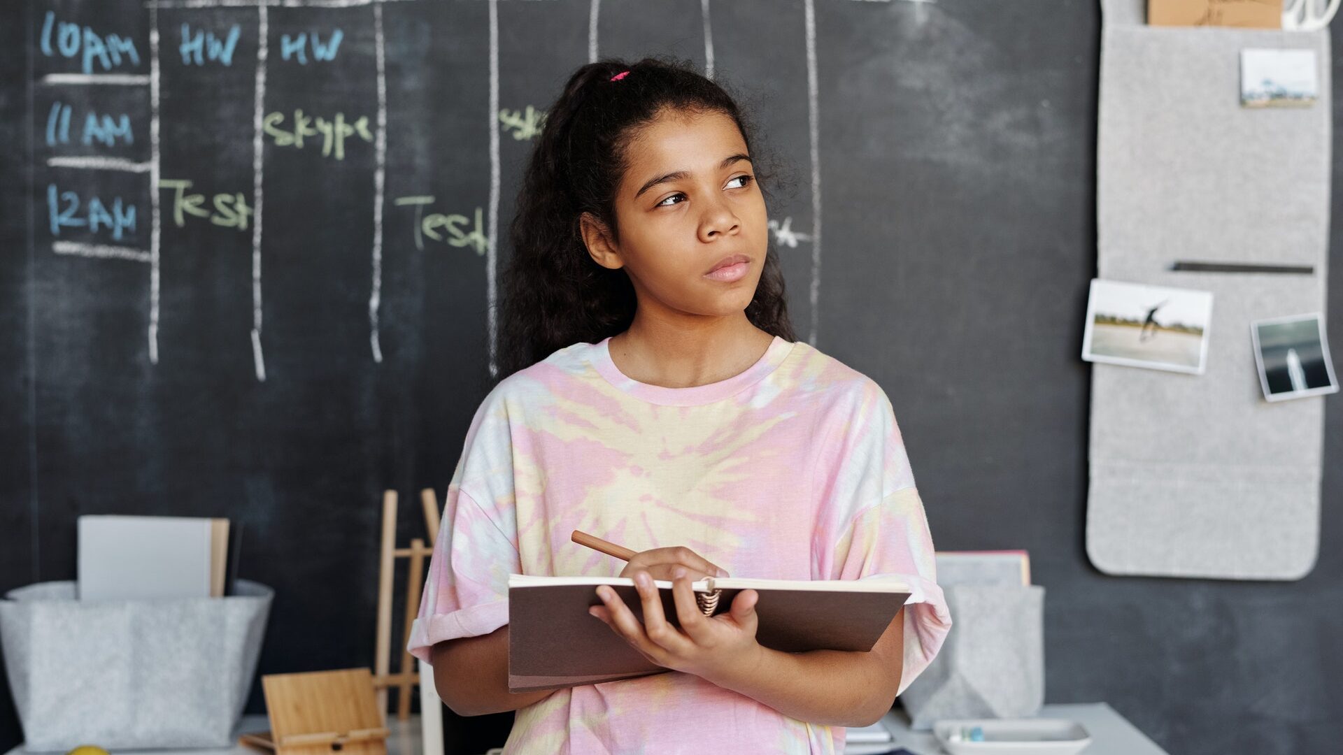 an asian girl holding a pencil and tablet thinking