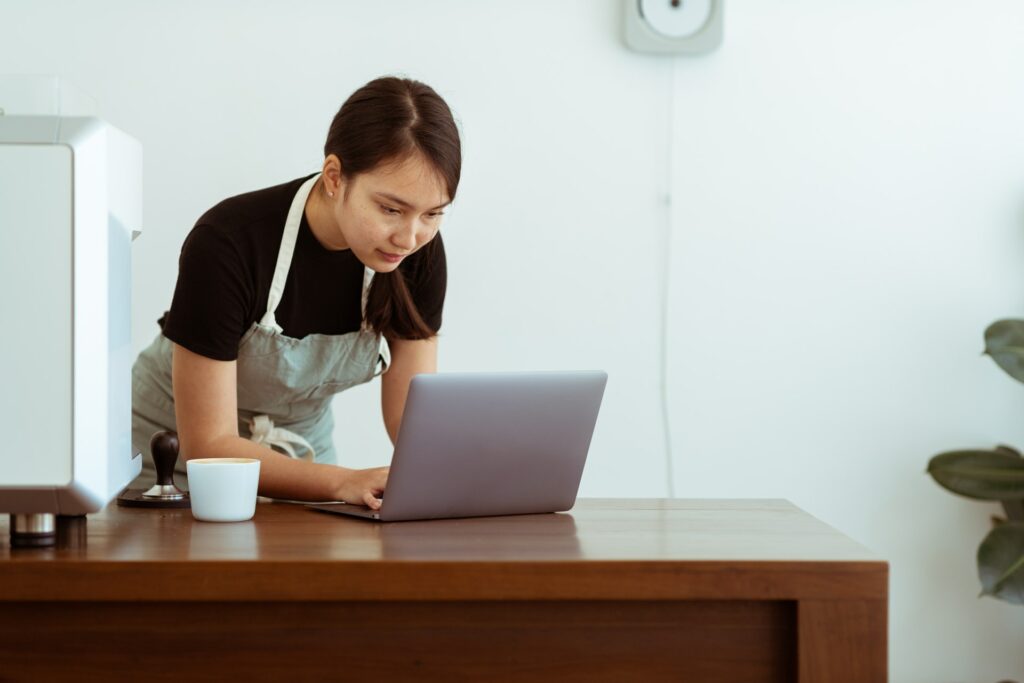 Focused woman in apron using laptop
