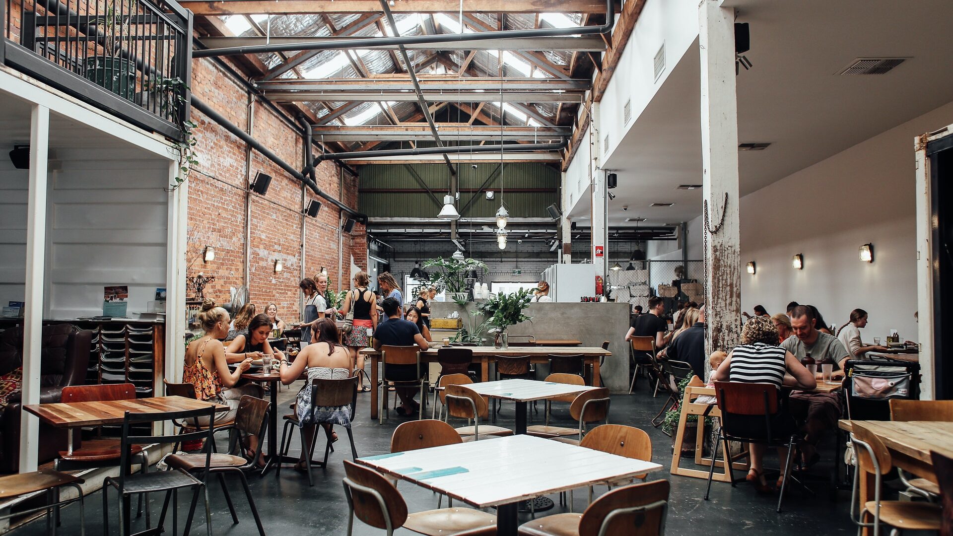 the interior of a restaurant with tables and a tall ceiling lots of natural light
