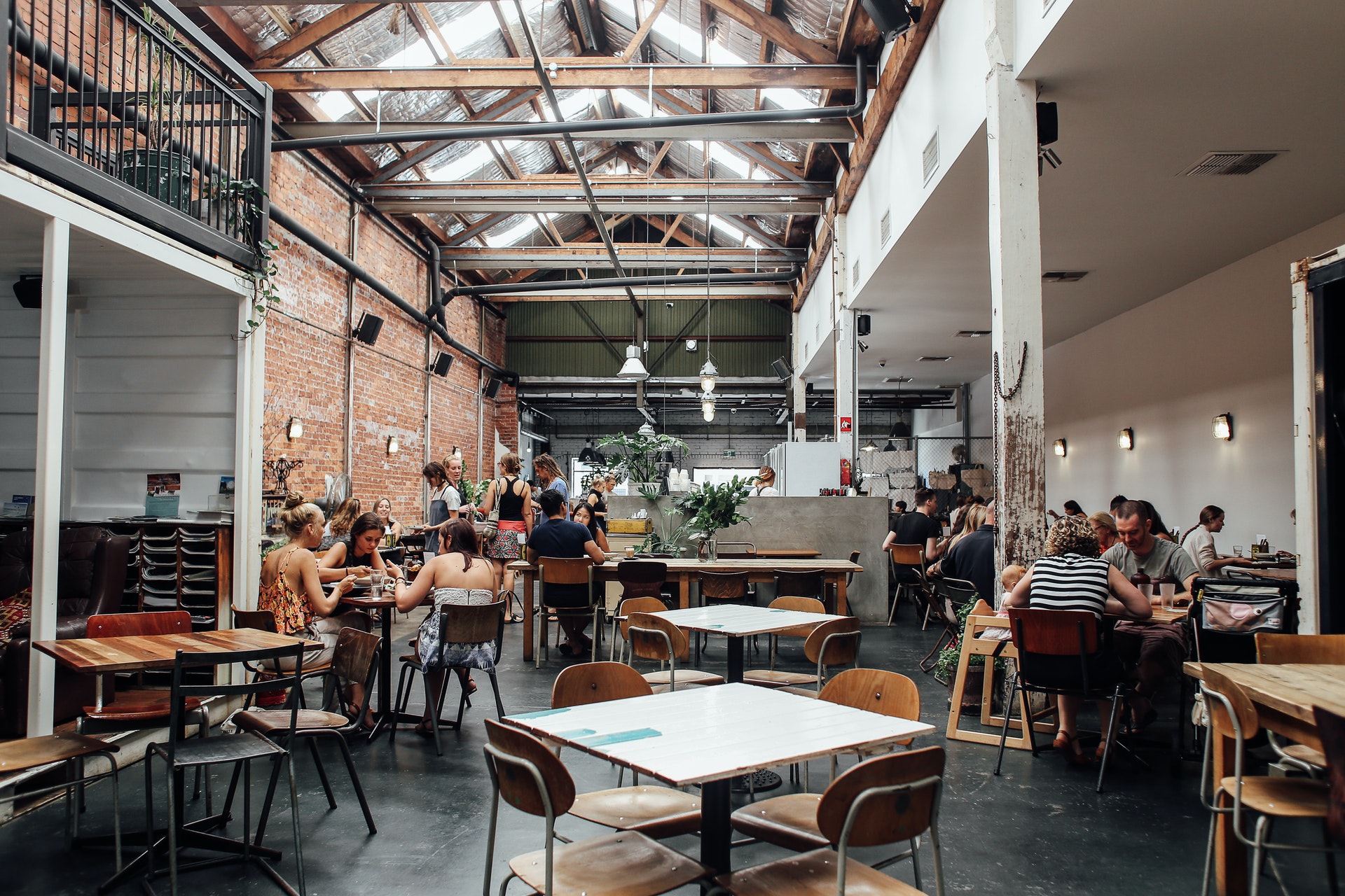 the interior of a restaurant with tables and a tall ceiling lots of natural light