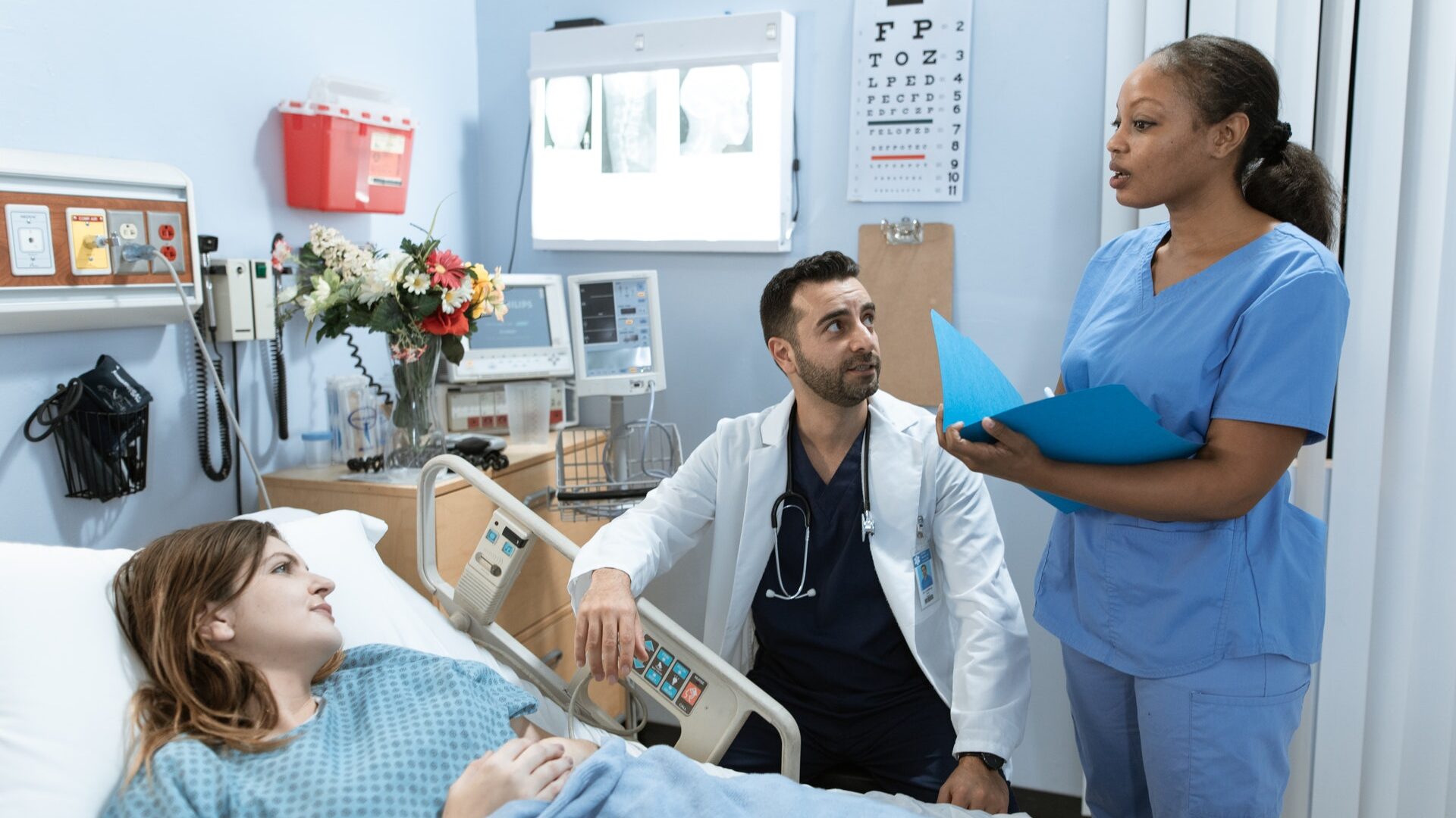 black woman nurse consulting with a white woman patient and male middle eastern doctor in medical office