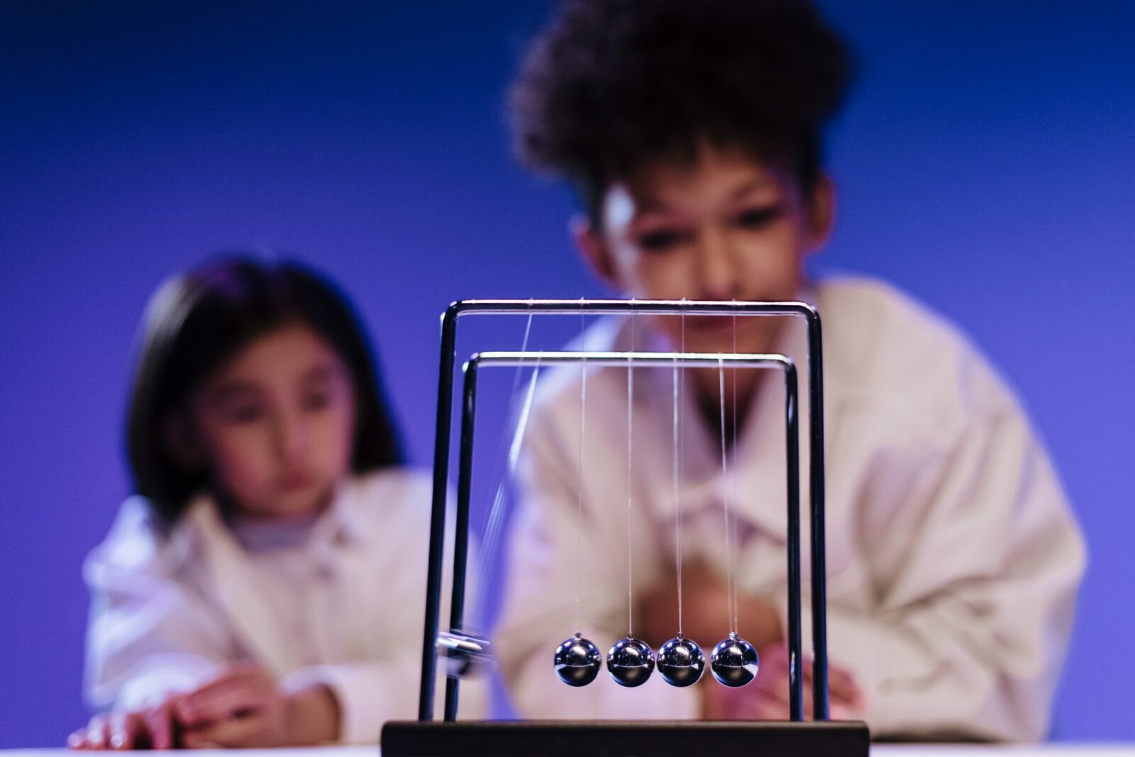 an asian child and a black child observing a toy