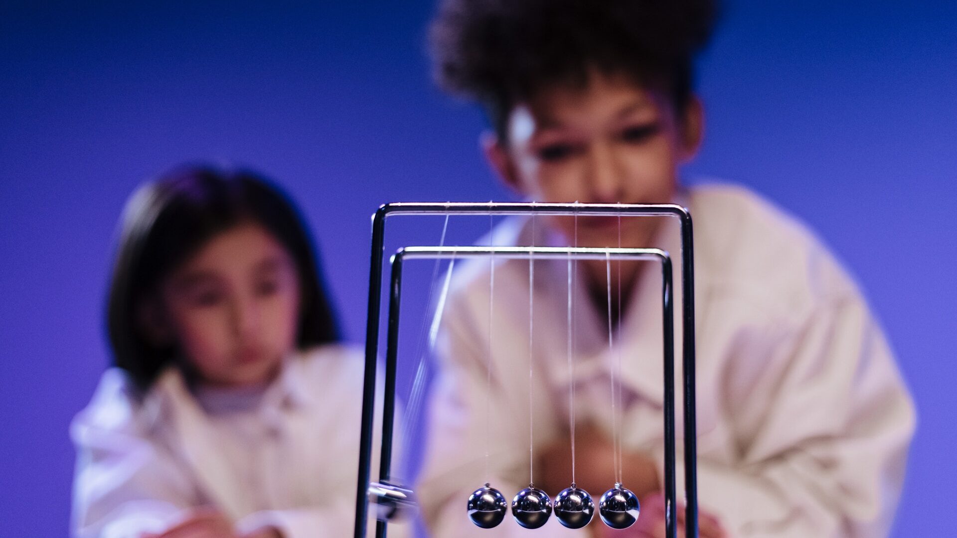 an asian child and a black child observing a toy