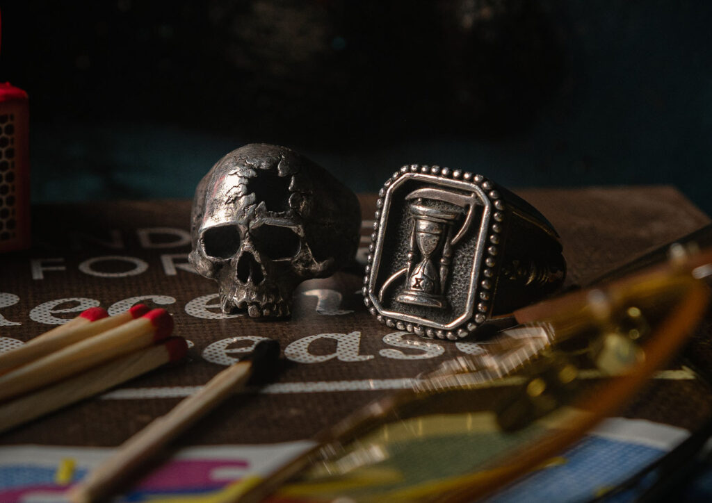 a skull ring and a ring with an hourglass on it sitting on a board game table